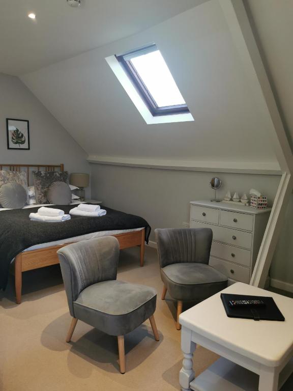 a bedroom with a bed and chairs and a skylight at Blakeney House in Blakeney