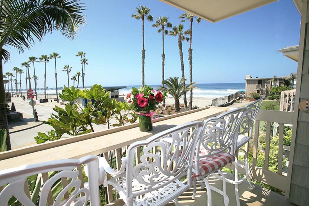 a balcony with two white chairs and a vase of flowers at D4 - Lighthouse on the Shore in Oceanside