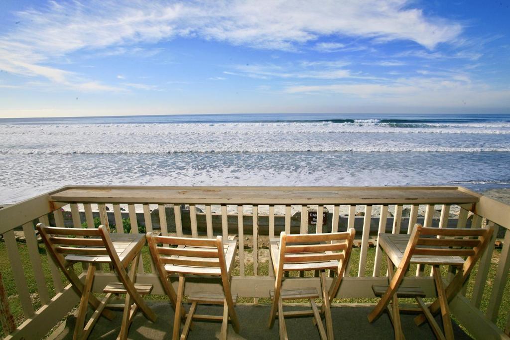 three chairs and a table on a balcony overlooking the ocean at D24 - Cottage on the Sand in Oceanside