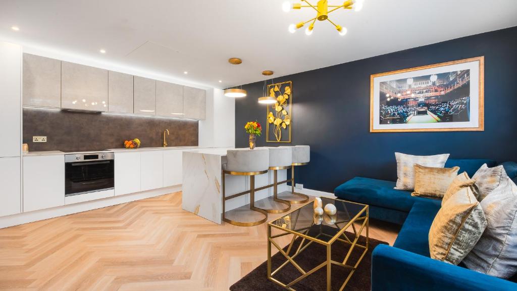 sala de estar con sofá azul y cocina en London's Modern Nuance Apartment - Battersea, en Londres