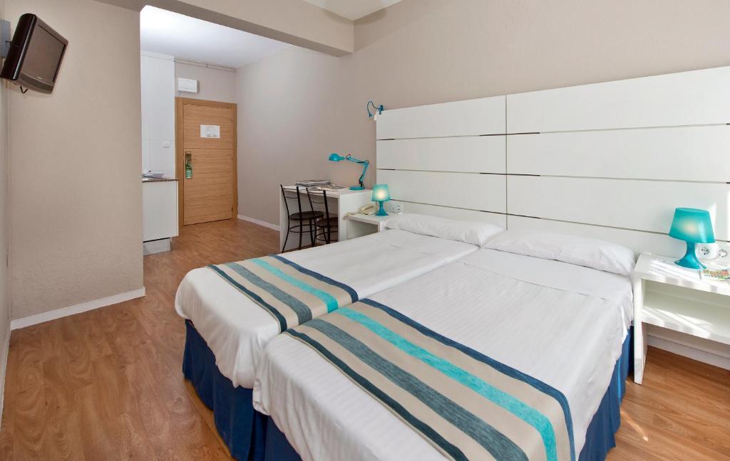 1 dormitorio con 1 cama blanca grande con manta a rayas en Estudios Aránzazu en Santander