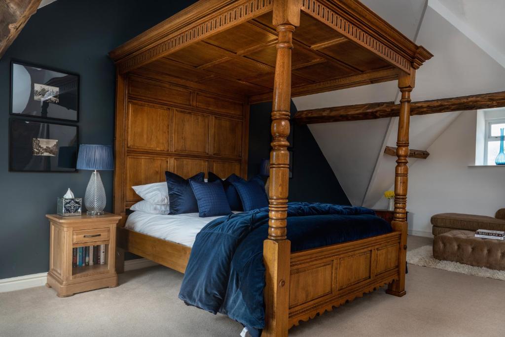 a bedroom with a wooden canopy bed with blue pillows at Castle View Townhouse in Conwy