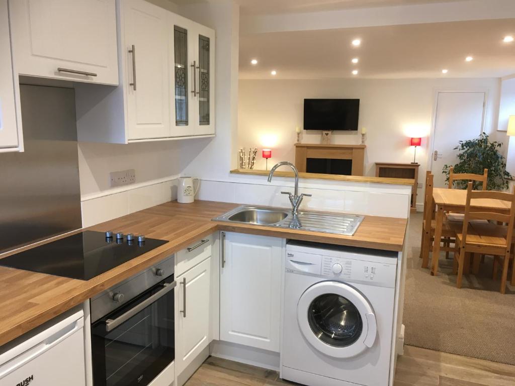 a kitchen with a washing machine and a sink at Crossways Corner Cottage in Gunnislake