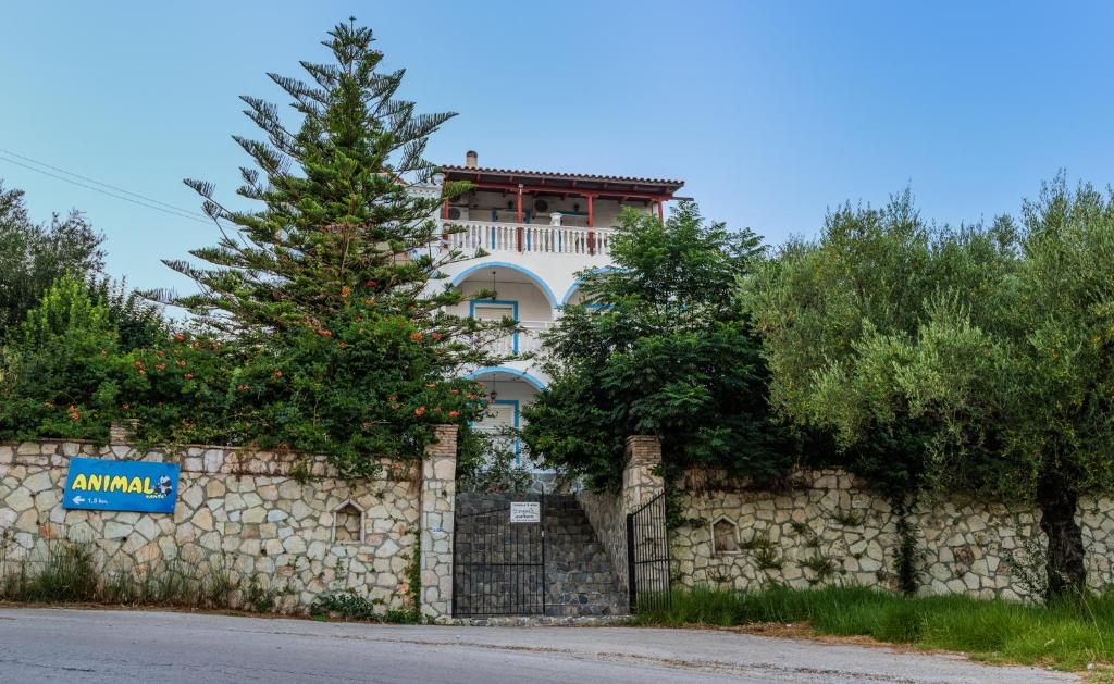 a building behind a stone wall with a tree at Tassos & Marios Apartments I in Laganas