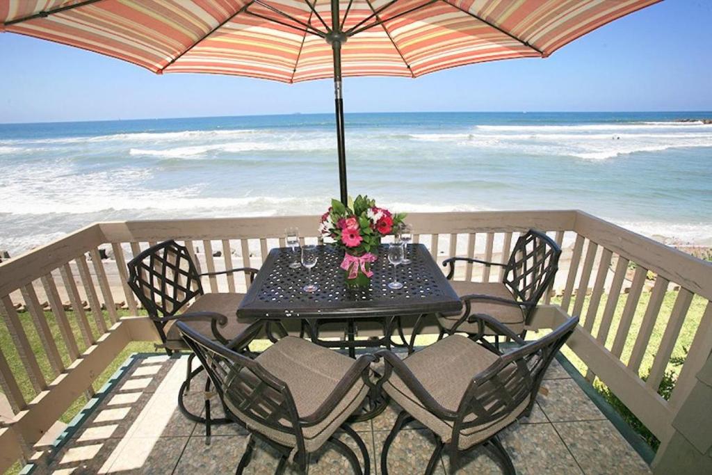 een tafel met stoelen en een parasol op het strand bij E20 - Tropical Paradise - On-the-Sand in Oceanside