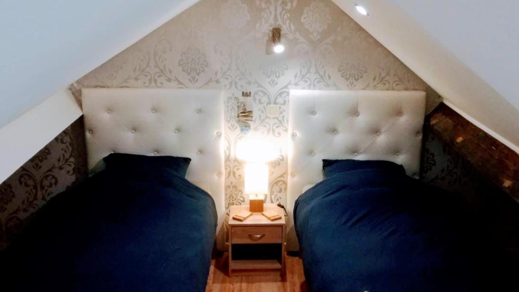 a bedroom with two beds and a table with a lamp at B&B De Schorre in Boom