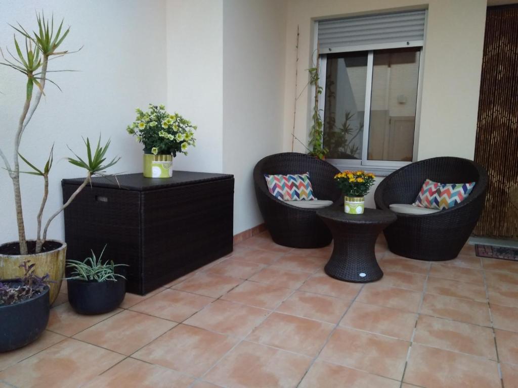 a patio with three wicker chairs and potted plants at Acogedor adosado muy cerca de la playa in Almazora