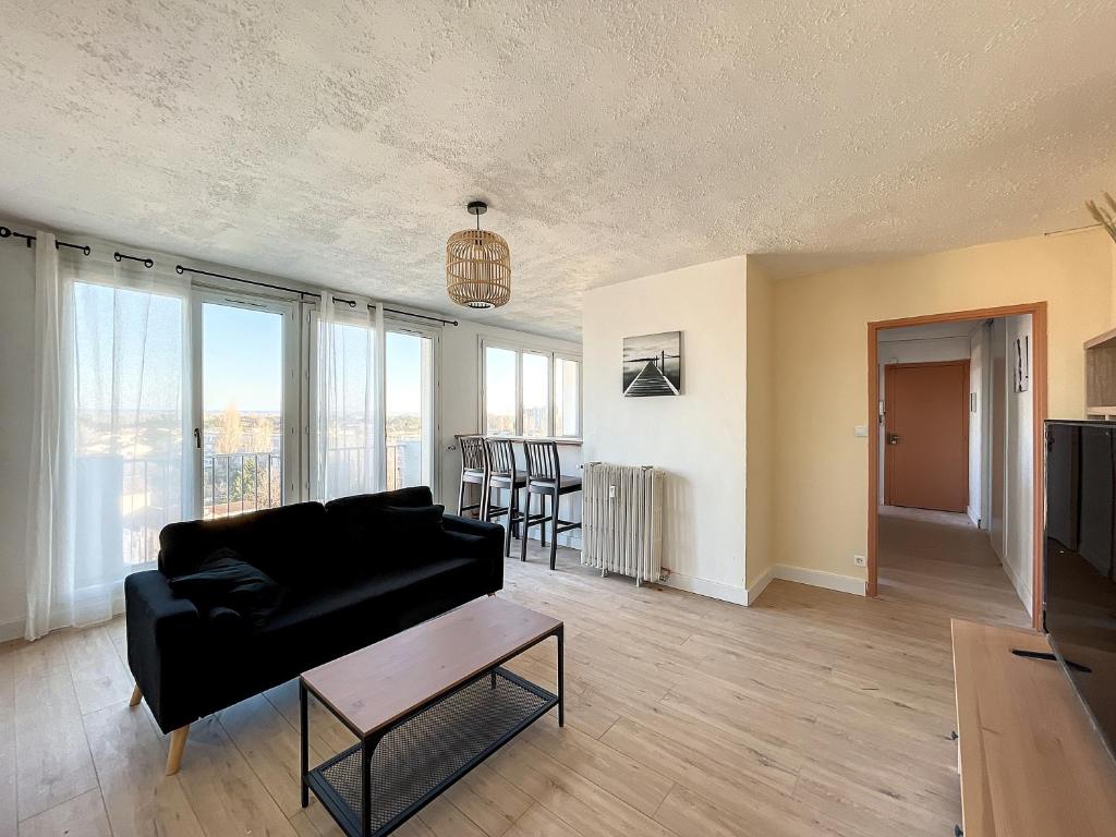 un salon avec un canapé noir et une table dans l'établissement Agréable appartement 4 pièces, vue Mont Ventoux, proche remparts, à Avignon