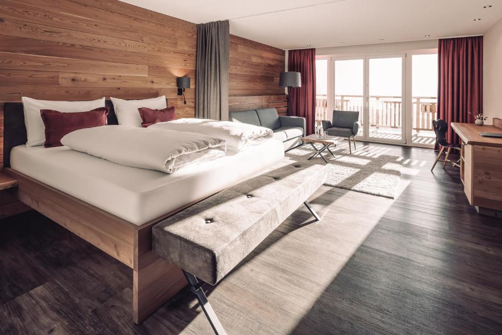 a bedroom with a large bed and a desk at Naturhotel Outside in Matrei in Osttirol