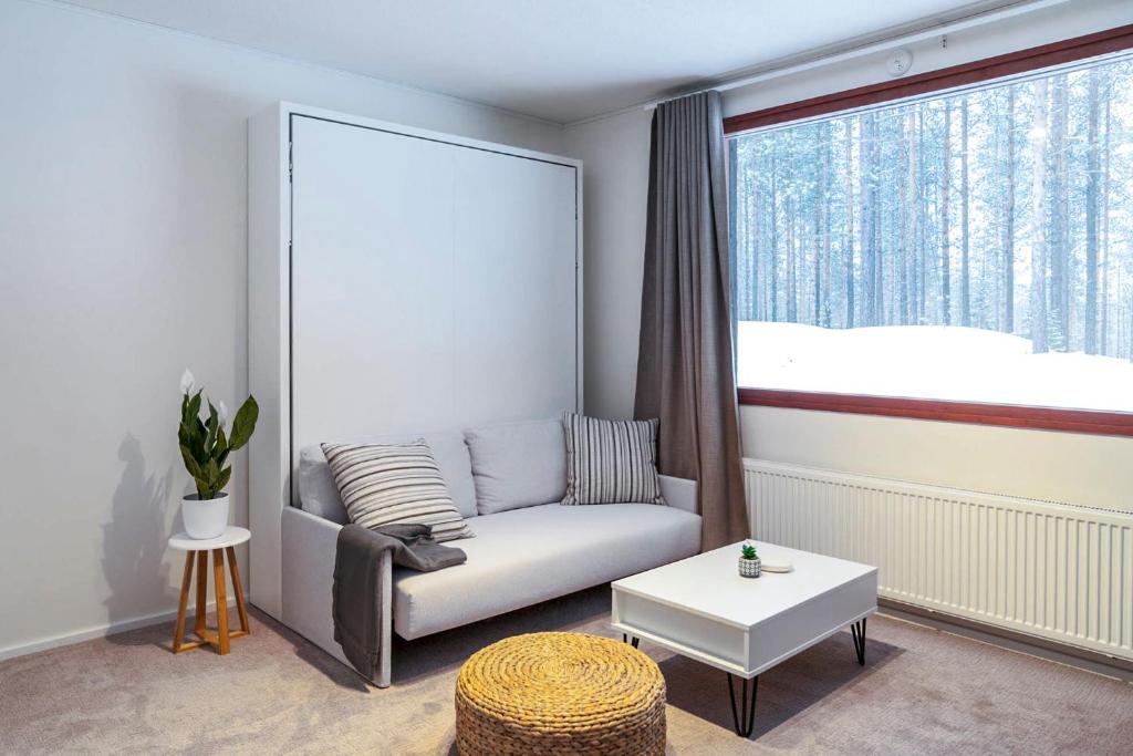 a living room with a couch and a large window at Holiday Apartment Usva Studio II in Suomutunturi