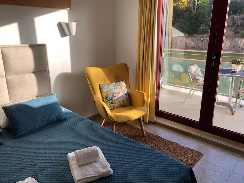 a bedroom with a bed and a chair and a window at Ericeira Surf and Sun in Ericeira