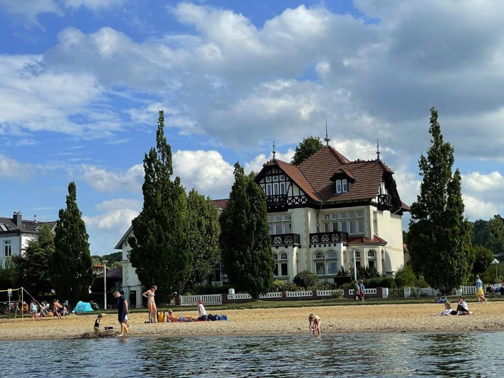 a group of people on the beach in front of a house at Apartment On The Beach, Schwerin in Schwerin