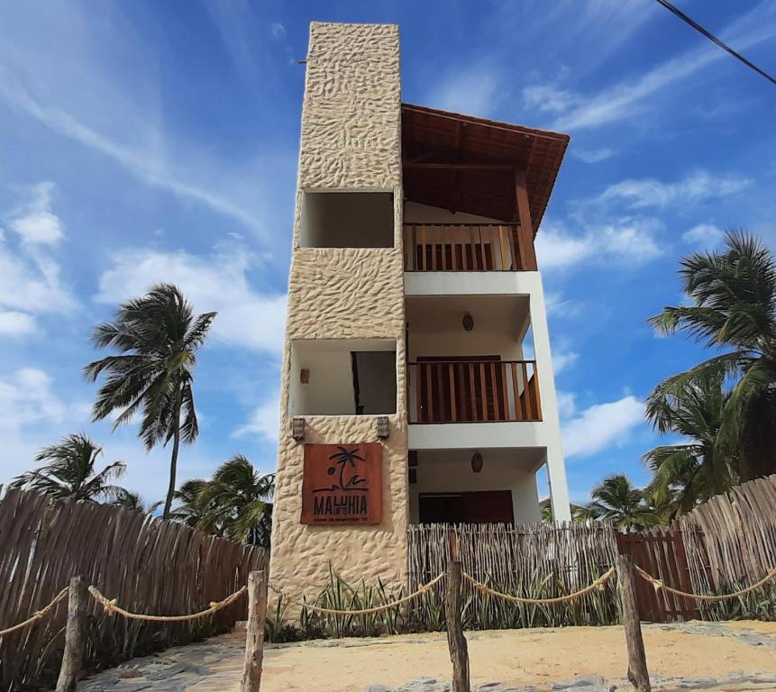a building on the beach with a fence and palm trees at Maluhia Lofts in Icaraí