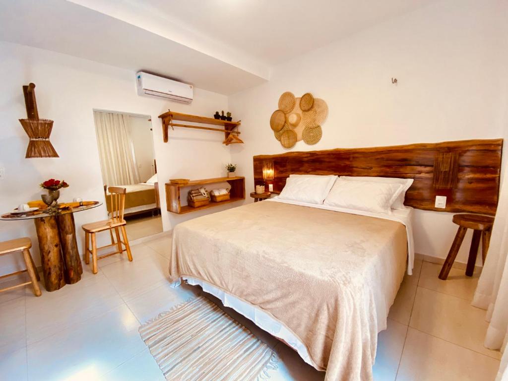 a bedroom with a bed and a table and chairs at Suítes Jardins de Flecheiras in Flecheiras