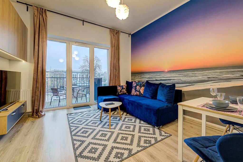 a living room with a blue couch and a view of the ocean at Sunset Studio - Free Parking - Fast Internet - Close to Everything in Poznań