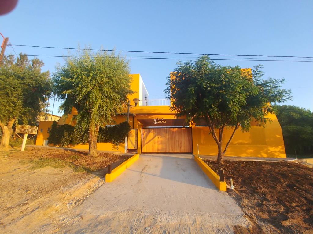 a yellow house with a garage and two trees at Ankara 3 in Las Grutas