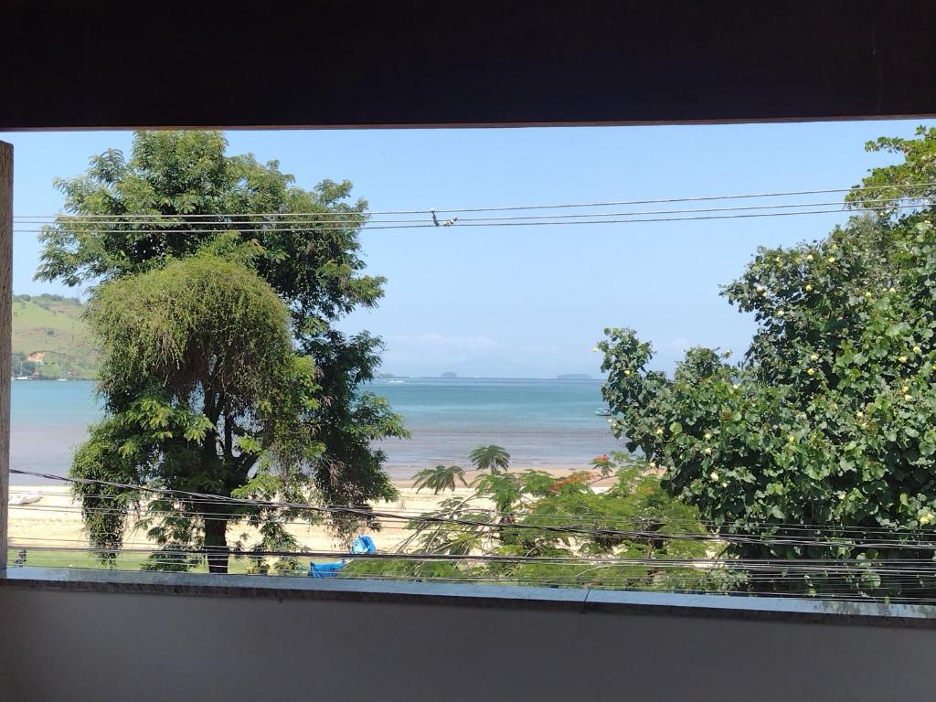 a view of the ocean from a window with trees at Bartole in Angra dos Reis