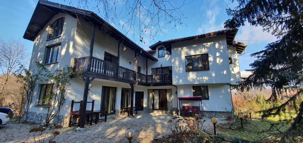 a large white house with a balcony on it at Guest House Ela in Dolna Banya