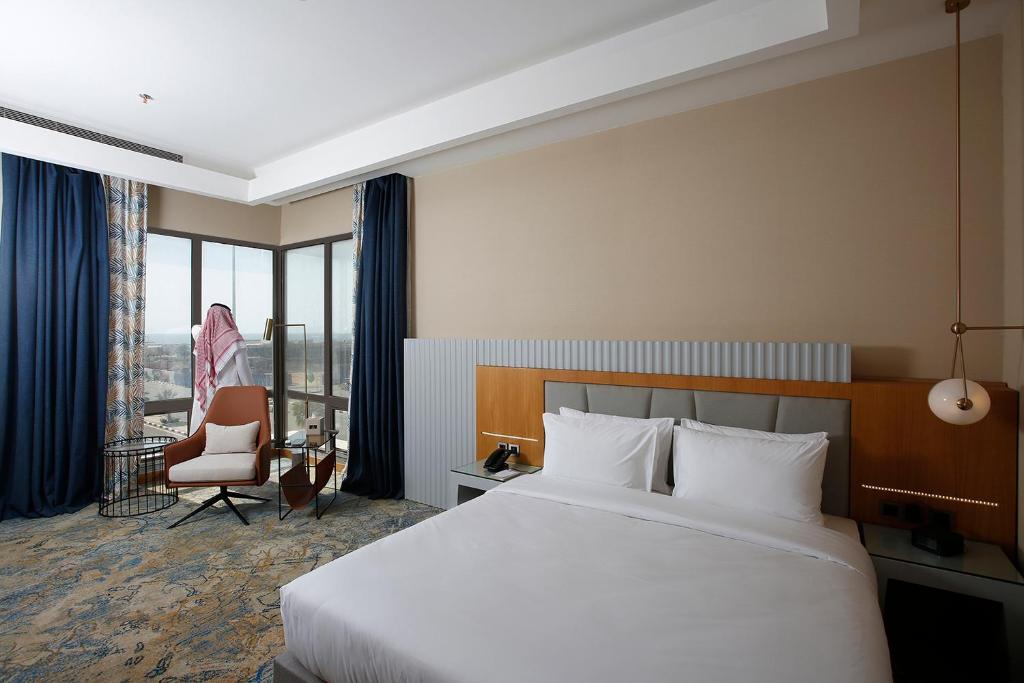 a hotel room with a large bed and a chair at Grand Plaza Hotel - Jazan in Jazan