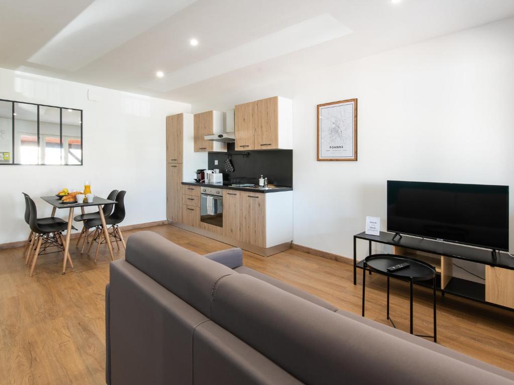 een woonkamer met een bank en een tafel en een keuken bij Aventures modernes in Roanne