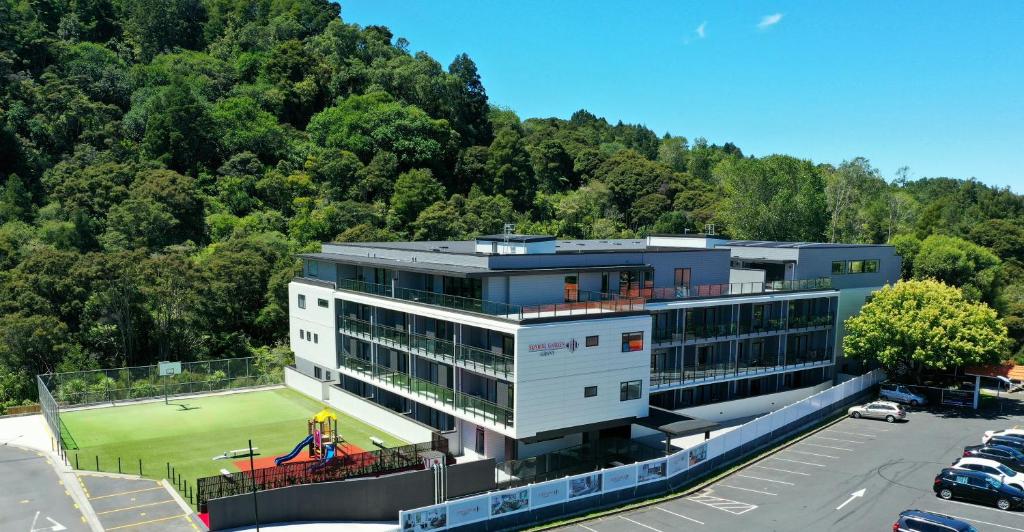 a building with a tennis court in a parking lot at Sunrise Garden Serviced Apartments Albany in Auckland