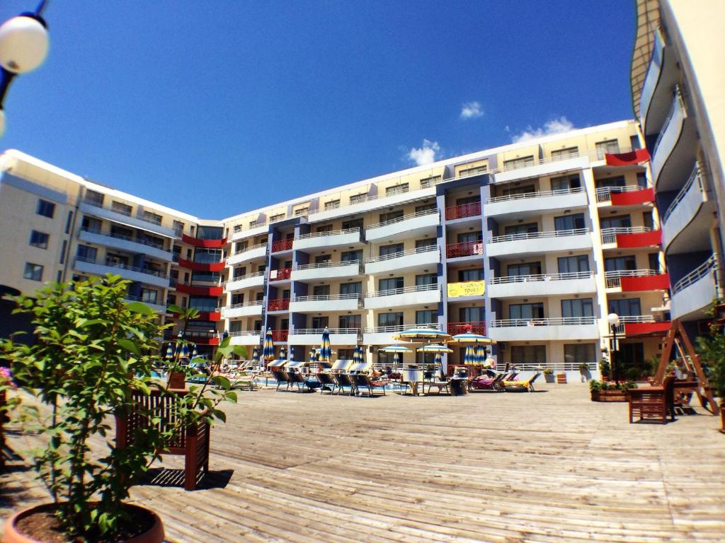 a large apartment building with people sitting outside of it at Apartments in Central Plaza in Sunny Beach