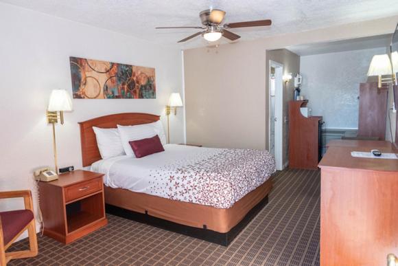 Habitación de hotel con cama y ventilador de techo. en Esquire Inn en Elko