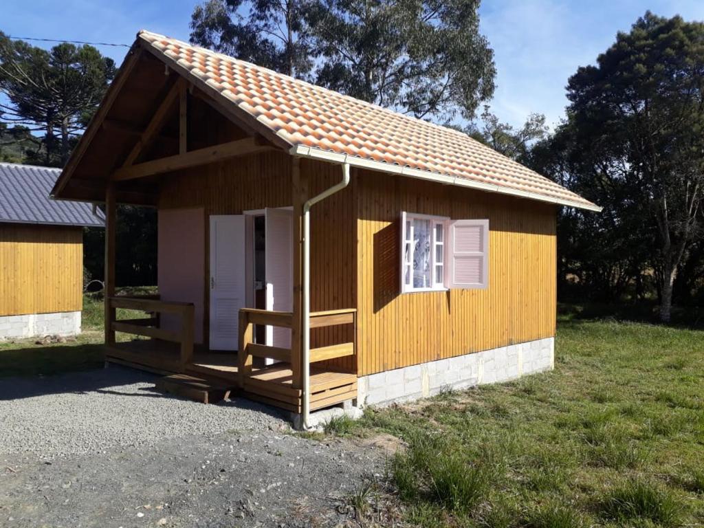 a small yellow building with a porch and a window at Pousada Cabanas Flor de Mel in Urubici