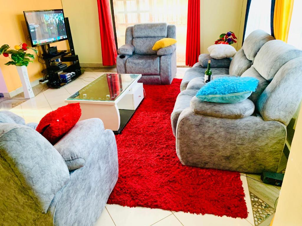 una sala de estar con 2 sofás y una alfombra roja en Yonga Apartment, en Kisumu