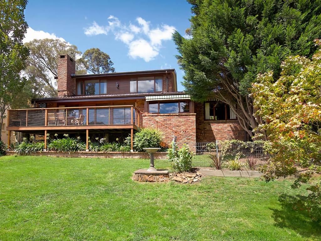 a large brick house with a deck on a yard at Stableford Lodge in Blackheath