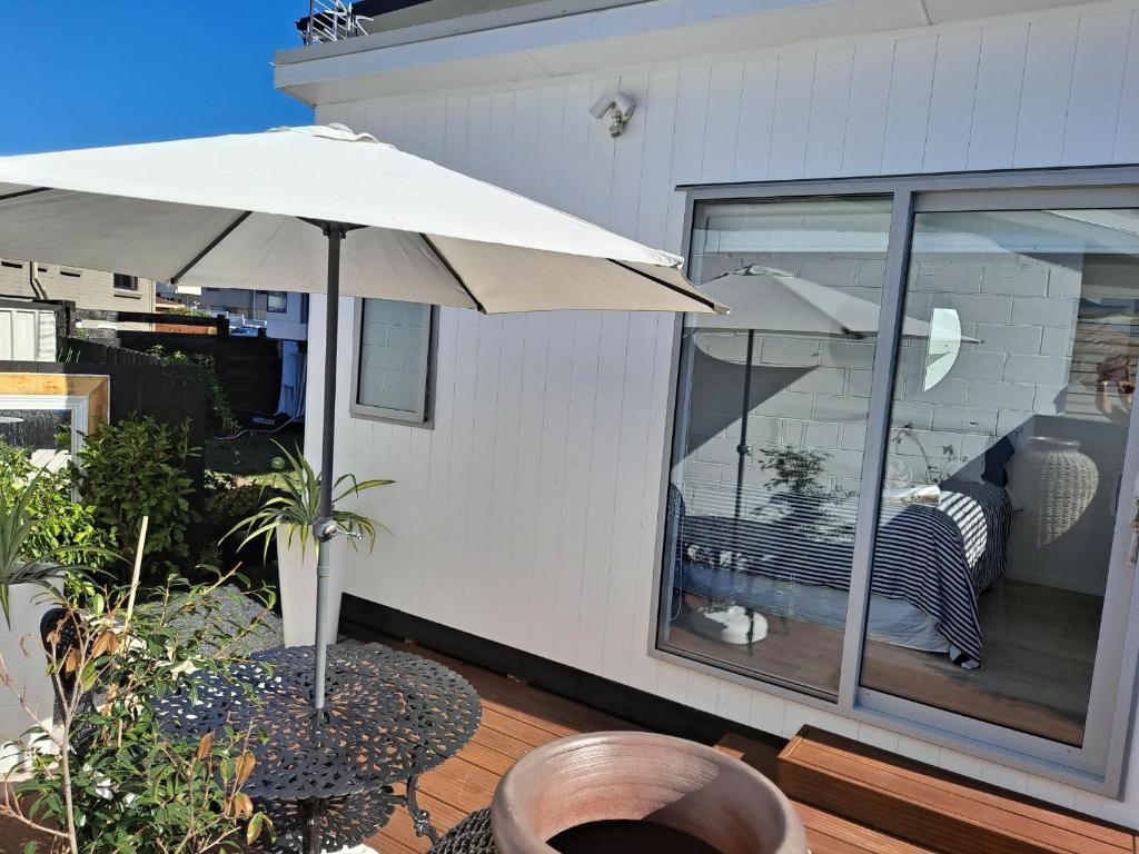 a patio with an umbrella and a table on a deck at Pod bach on Tweed in Tauranga