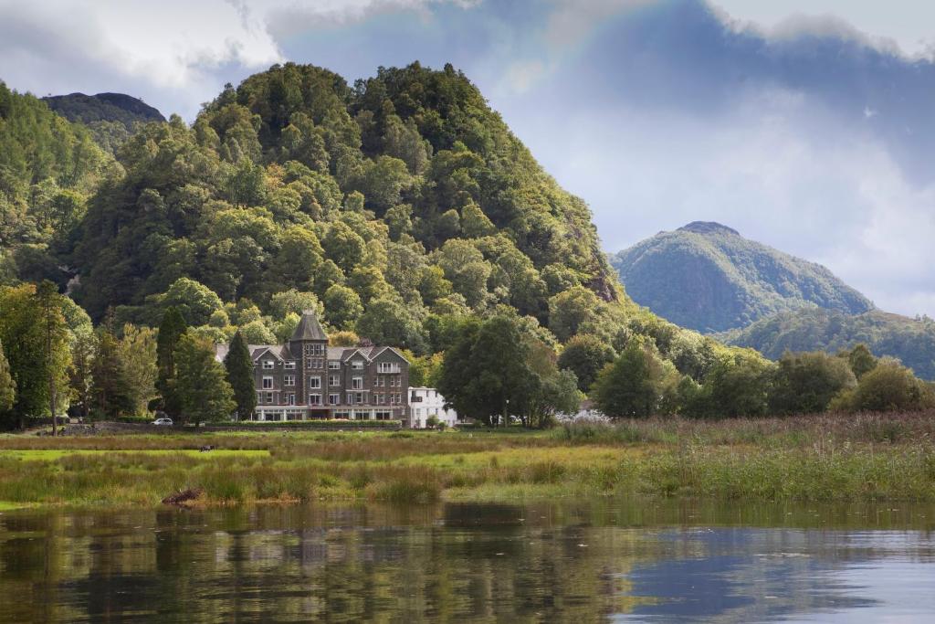 ein Haus vor einem Berg neben einem See in der Unterkunft Lodore Falls Hotel & Spa in Keswick