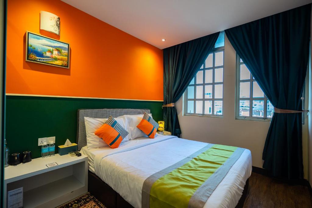 a bedroom with a bed with an orange wall at Link Hotel in George Town