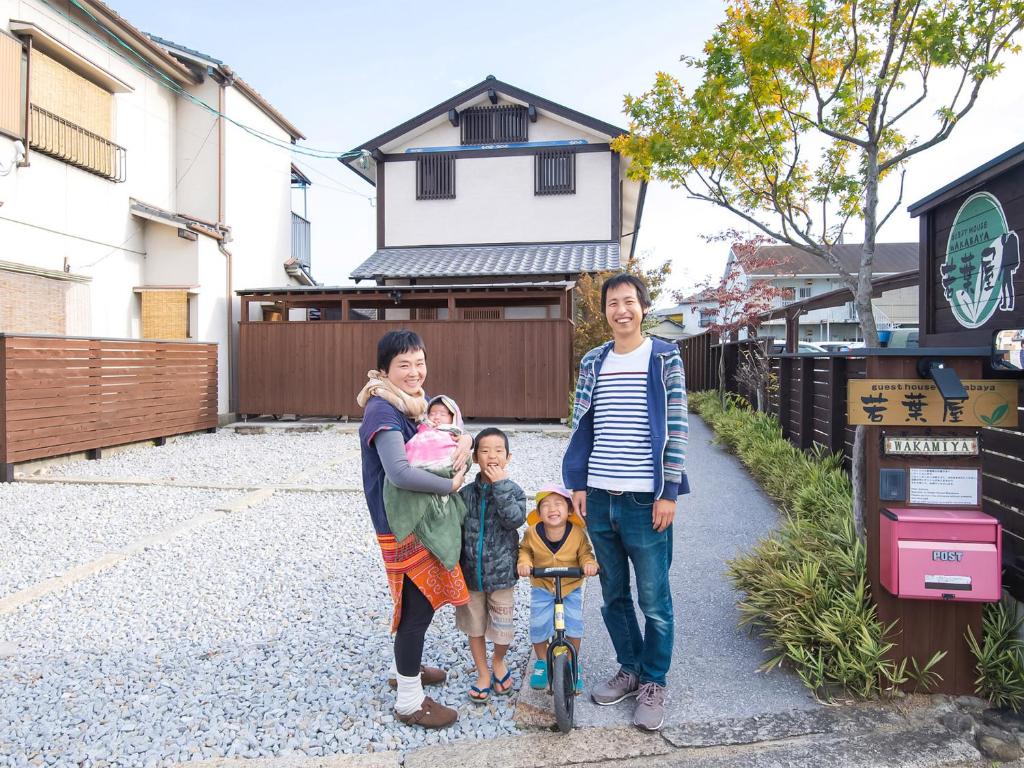 une famille posant une photo devant une maison dans l'établissement Guest House Wakabaya, à Takamatsu