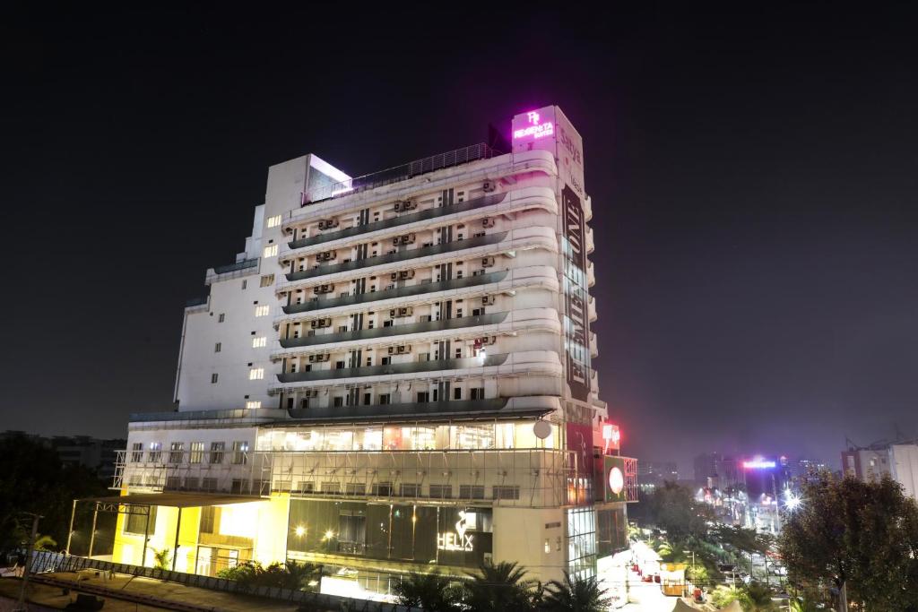 ein hohes weißes Gebäude mit rosa Licht darauf in der Unterkunft Regenta Suites Gurugram, Sohna Road, Sector 49 in Gurgaon