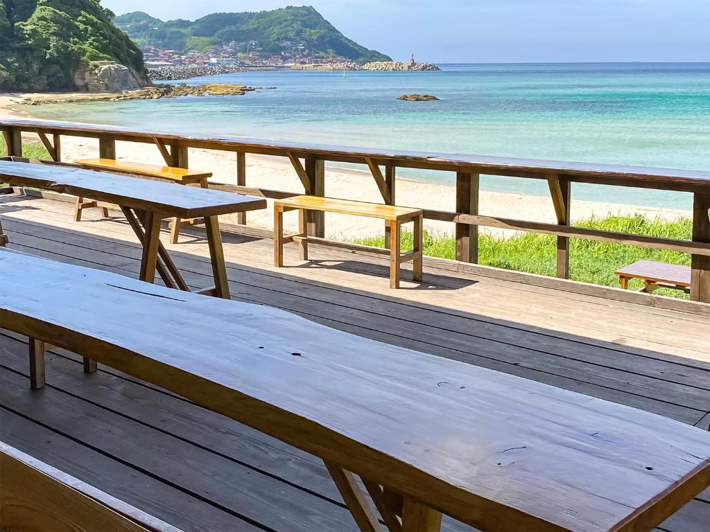 a wooden deck with picnic tables on the beach at Sea Breeze 1987 in Nagato