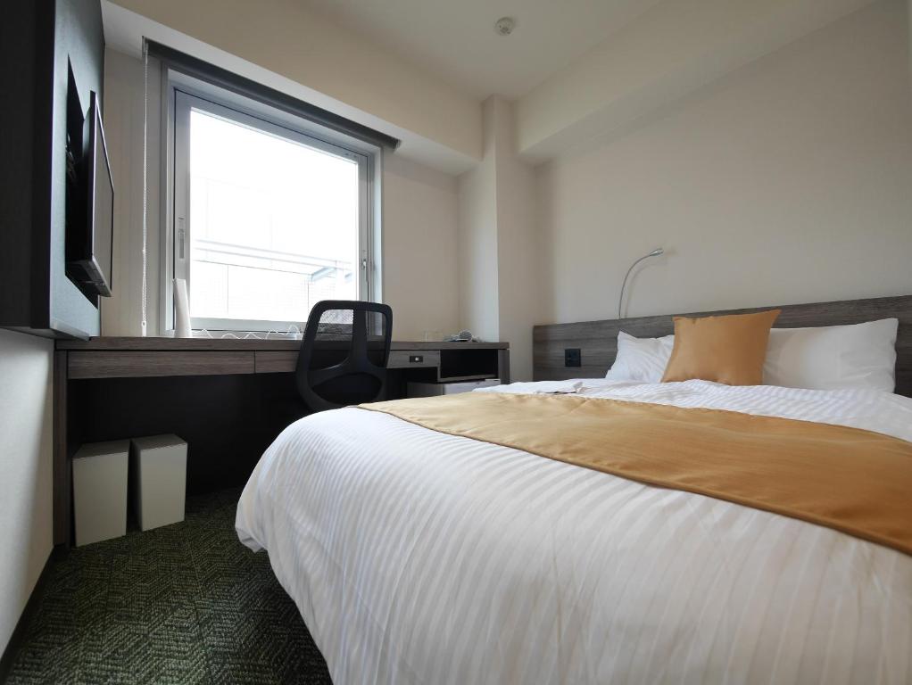 - une chambre avec un grand lit et une fenêtre dans l'établissement Hotel Comfybed Ginza, à Tokyo