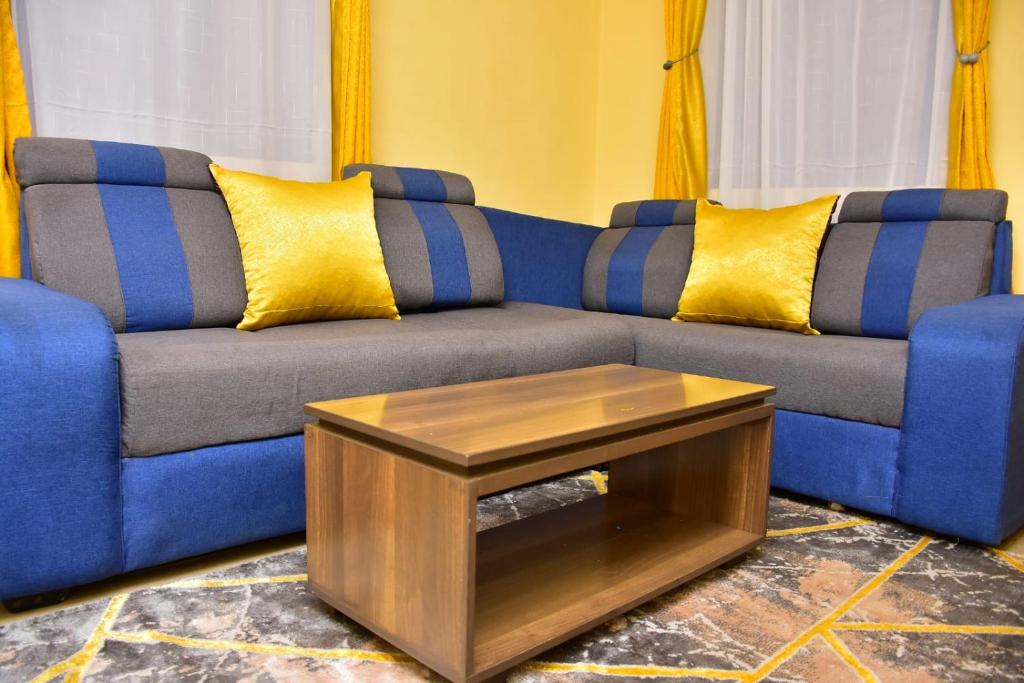 - un canapé bleu avec des oreillers jaunes et une table basse dans l'établissement Lux Suites Imperial Heights Ruiru, à Ruiru