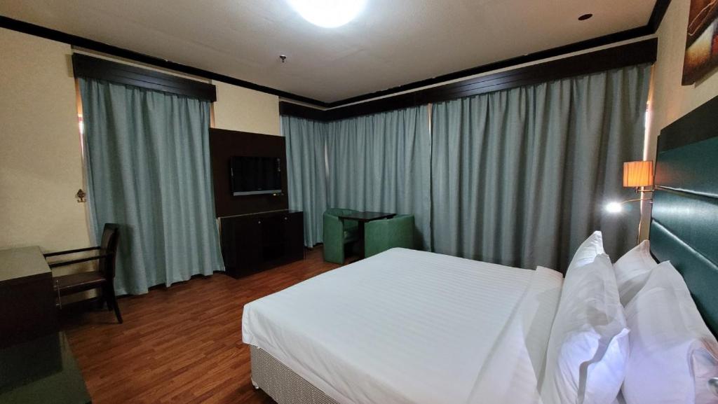 a hotel room with a white bed and a television at Strand Hotel in Abu Dhabi