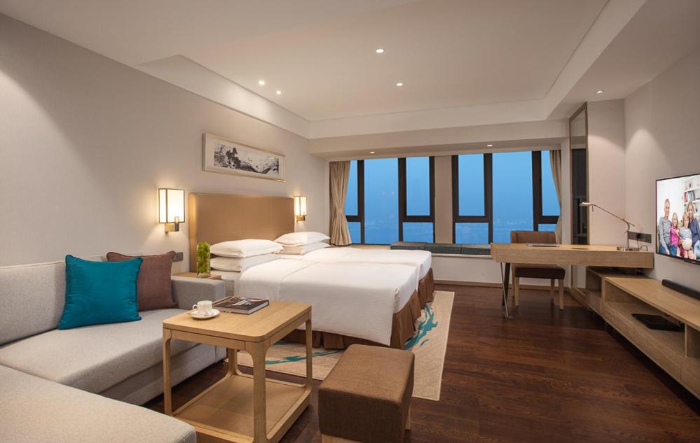 a hotel room with a bed and a couch at Somerset Yangtze River Chongqing in Chongqing