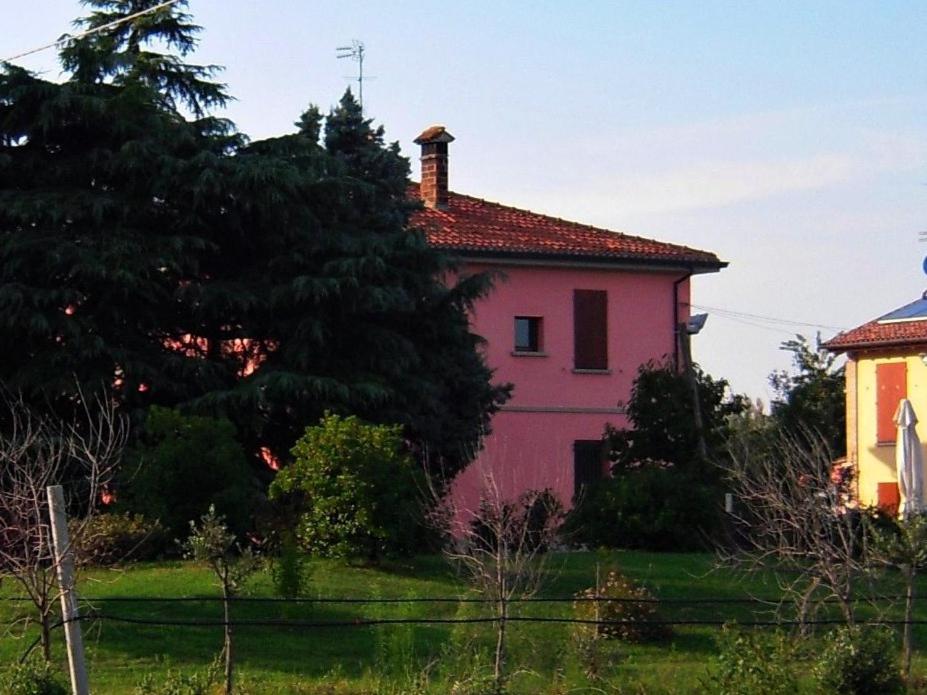 une maison rose au milieu d'un champ dans l'établissement Agriturismo La Prosciutta, à Faenza