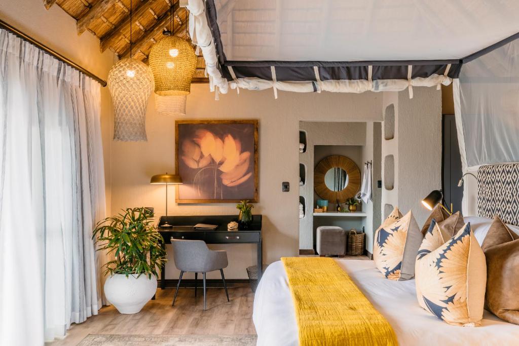a bedroom with a large bed and a desk at Thornybush Simbambili Lodge in Sabi Sand Game Reserve
