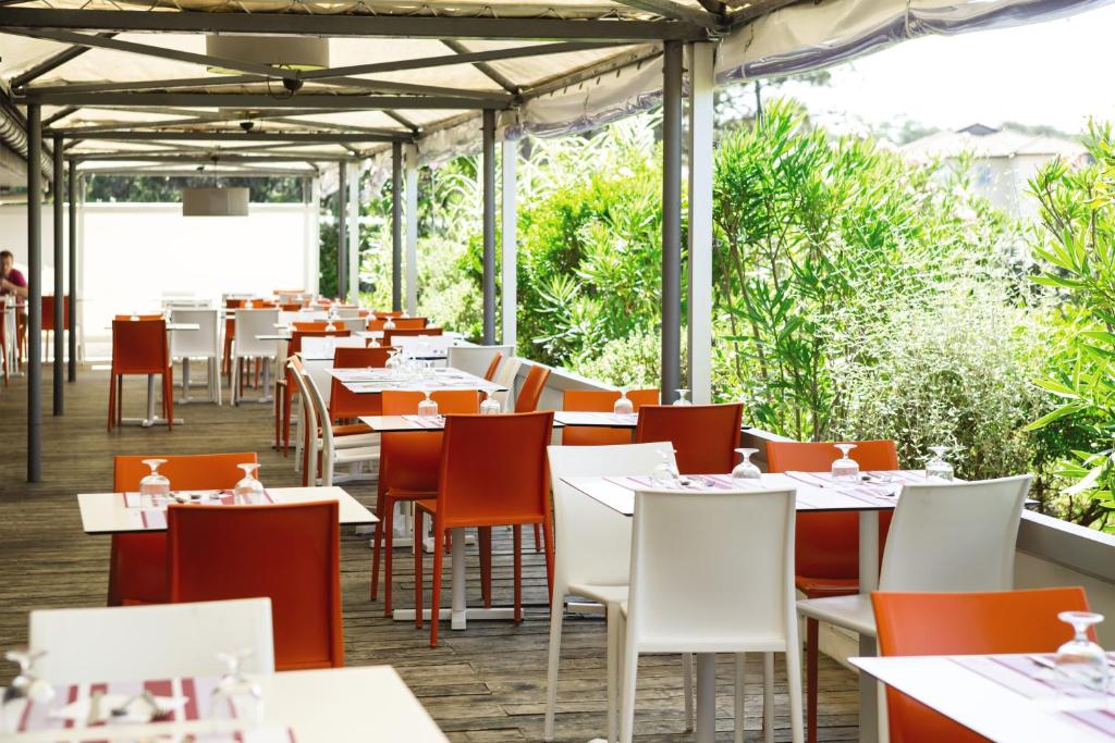 a restaurant with white tables and chairs and plants at Belambra Clubs Capbreton - Les Vignes in Capbreton