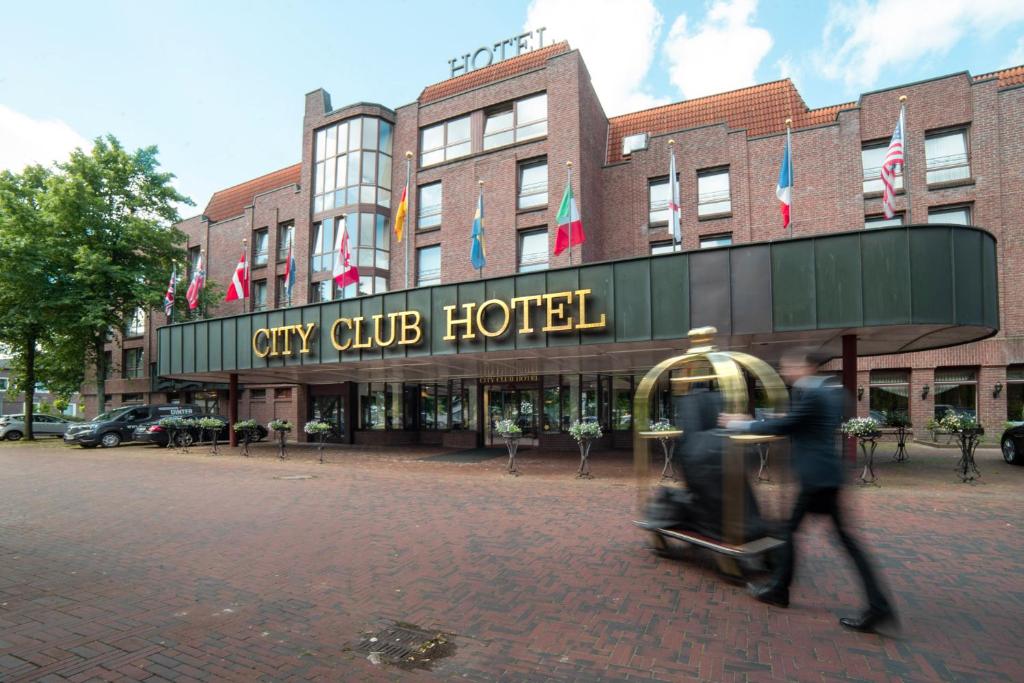 un par de personas caminando frente a un hotel en City Club Hotel en Oldenburg