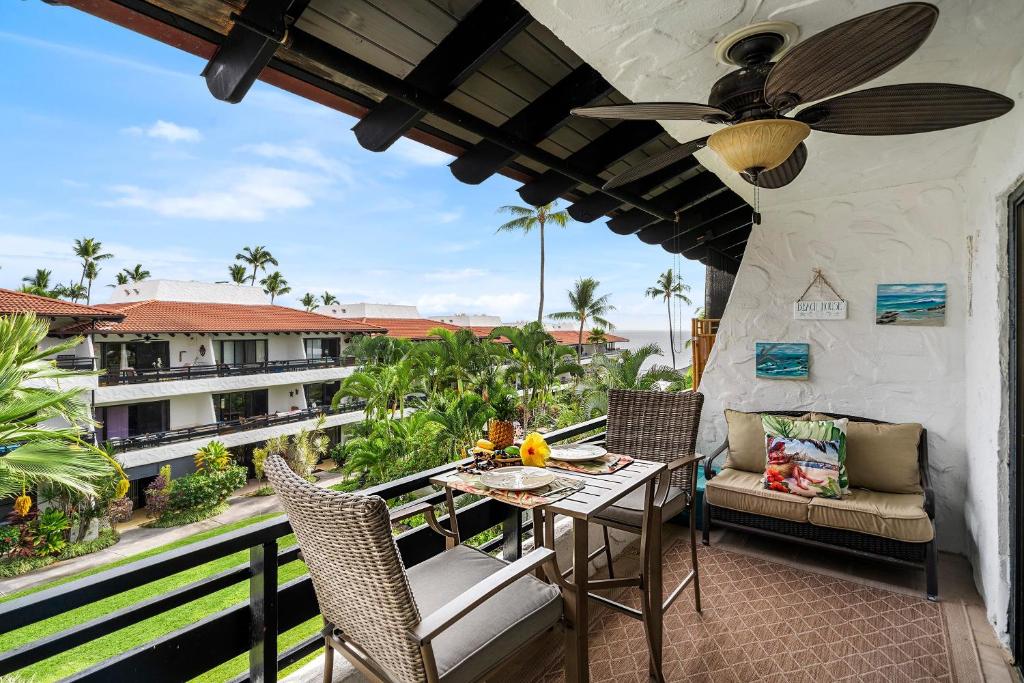 a balcony with a table and chairs and a ceiling fan at Casa De Emdeko 324 in Kailua-Kona