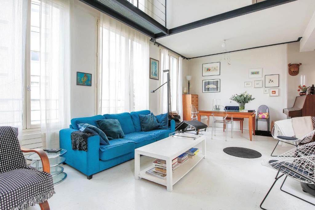 ein Wohnzimmer mit einem blauen Sofa und einem Tisch in der Unterkunft Veeve - White House in Paris