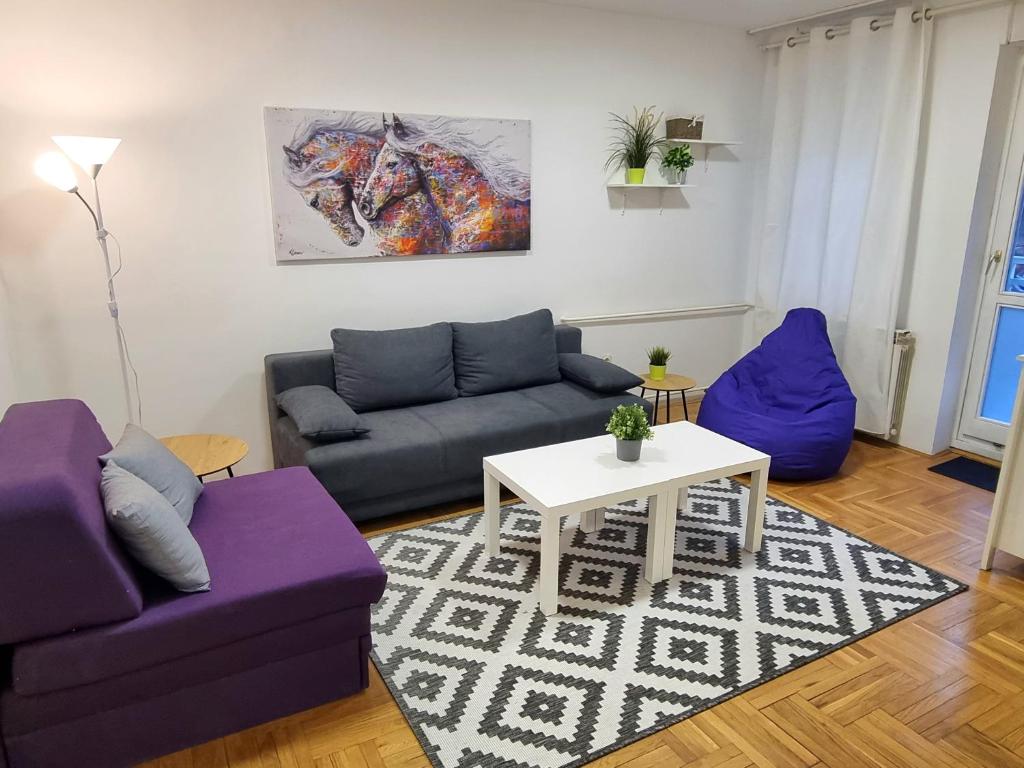a living room with two purple couches and a table at Klara 23 in Tošin Bunar