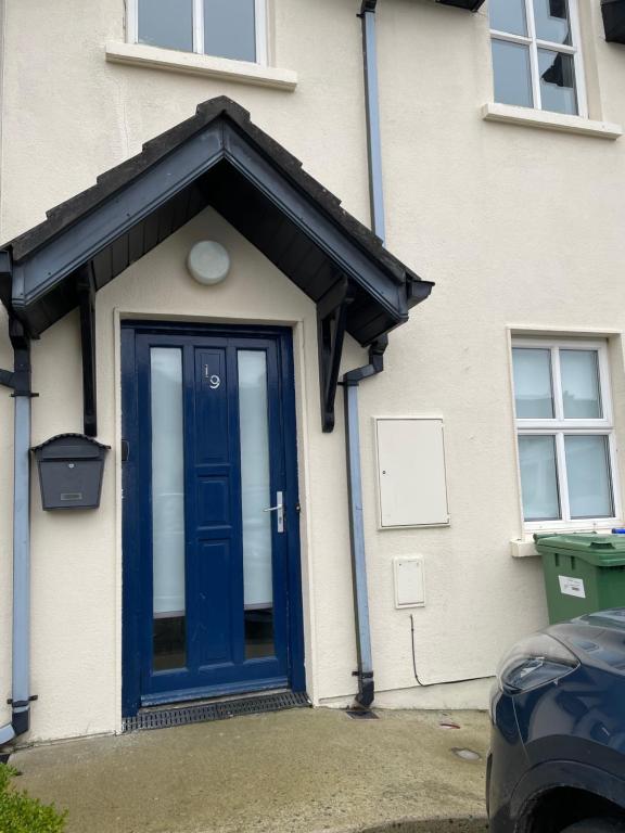 una puerta azul en una casa blanca con un adorno negro en Ballyhack by the Sea, en Arthurstown