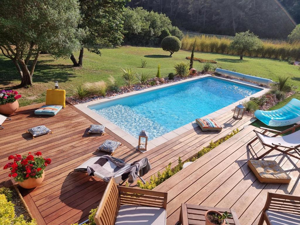 einen Hinterhof mit einem Pool und einer Holzterrasse in der Unterkunft Les Prairies de Fenestrelle Spa & Piscine au calme in Aubagne