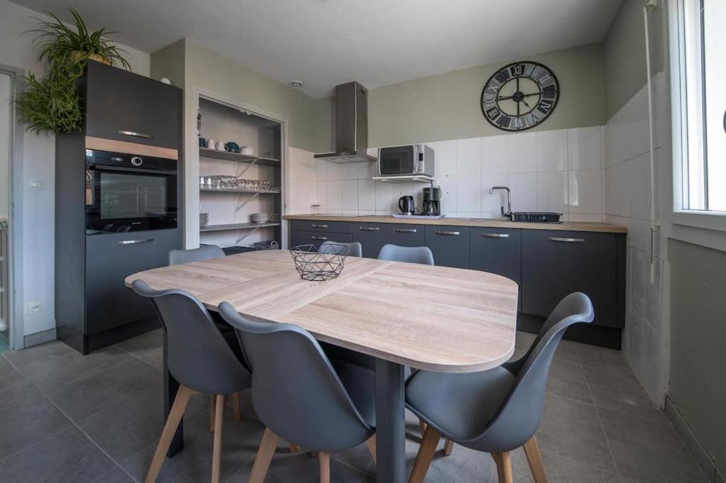 een keuken met een houten tafel en stoelen en een klok bij La douce-Maison-jardin in Montauban